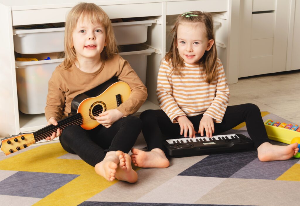 Happy children playing musical instruments at home. Sisters have fun in the room