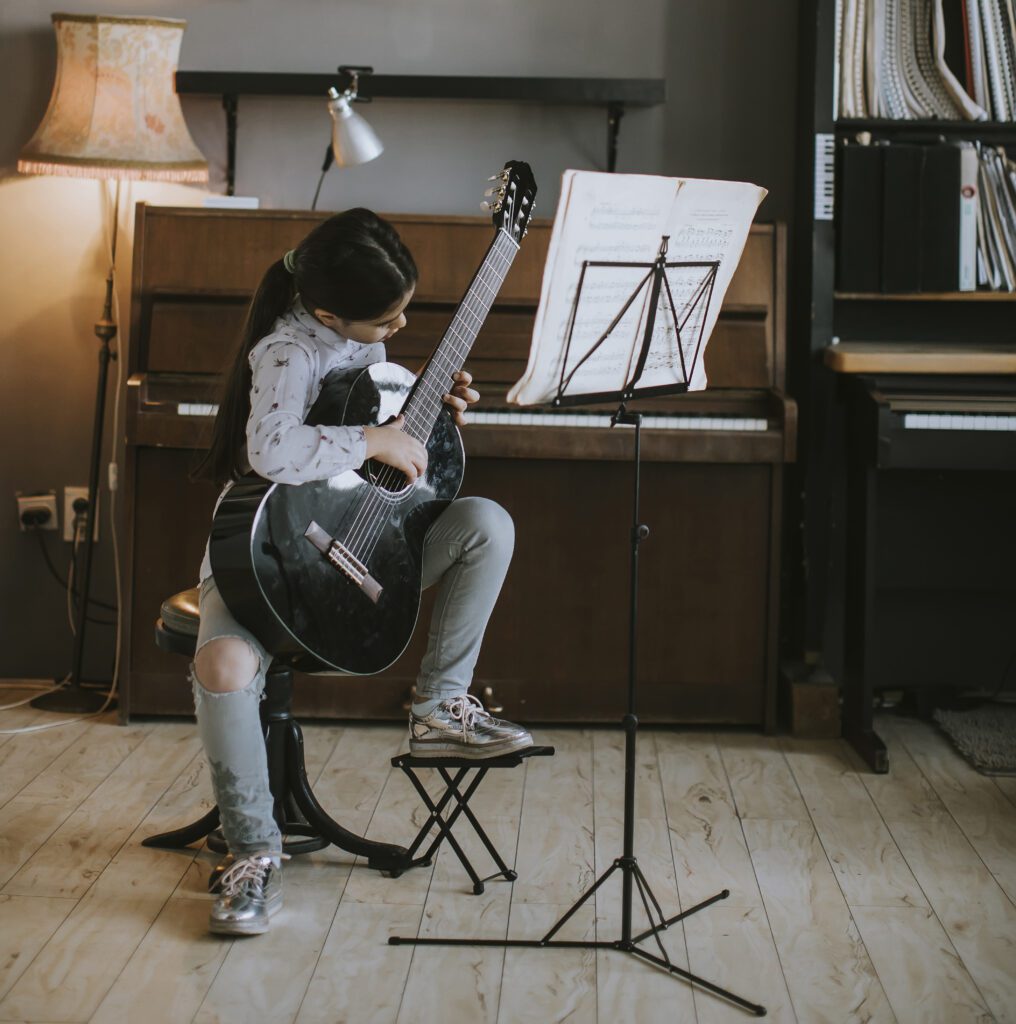 Cute little girl practicing on a acoustic guitar at rustic home