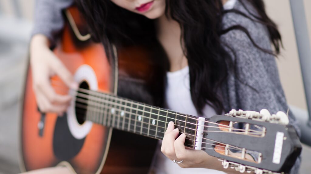 Close-up of a woman's hands gracefully playing guitar strings, showcasing skill and musicality.
