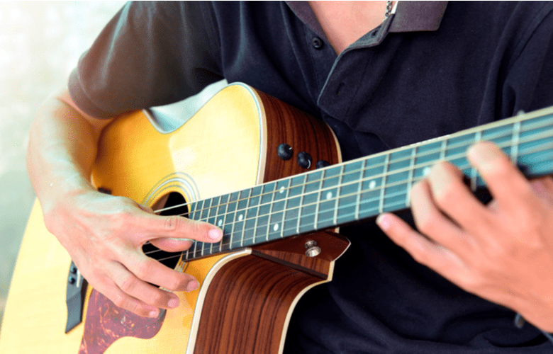 Man playing guitar trying to master guitar strings