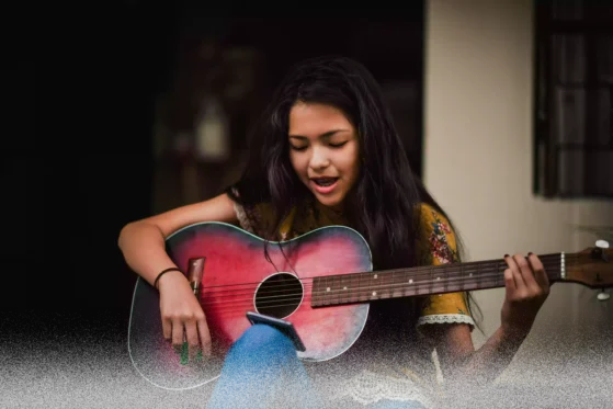 girl playing guitar used as a featured image on the page for guitar lessons online