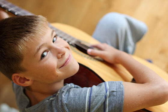 Boy smiling with guitar | Learn electric guitar at 12