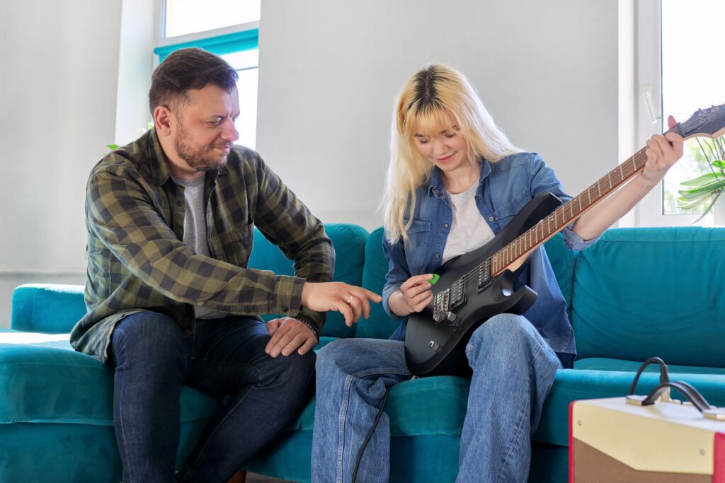 Father teaching teen daughter to play electric guitar. to make her master electric guitar musician