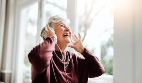 Patient in hospital bed listening to soothing music through headphones – therapy medical uses for pain relief.