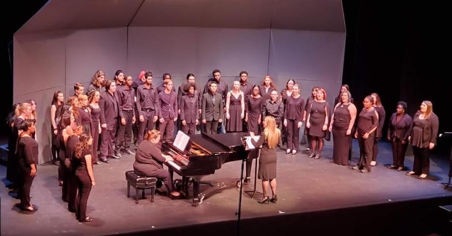 A choir ensemble performing on stage with a pianist and conductor during a live concert, showcasing the Role of Harmony in Competitive Choir Performances through vocal blending, teamwork, and musical coordination.