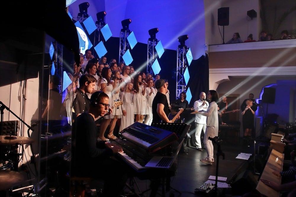 A live church worship team performing on stage with singers, keyboard players, and musicians under colorful stage lights, representing smooth transitions between worship chords during a modern worship service for beginner worship musicians.