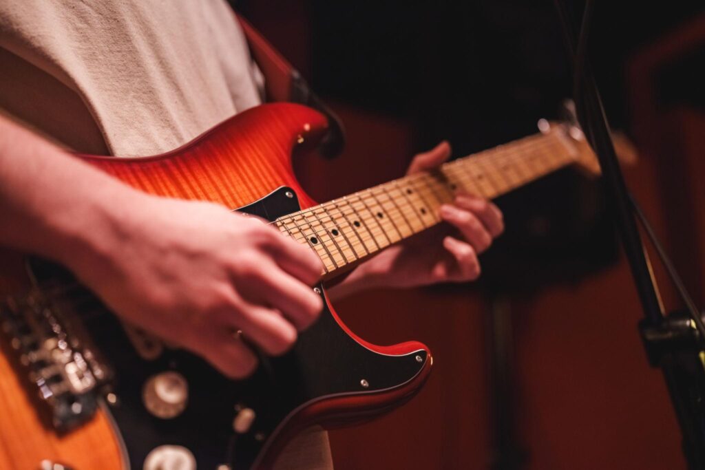 Close-up of a musician playing a red electric guitar with warm stage lighting, highlighting lead guitar techniques and melodic worship playing for “How to Play Lead Guitar in a Worship Band.”