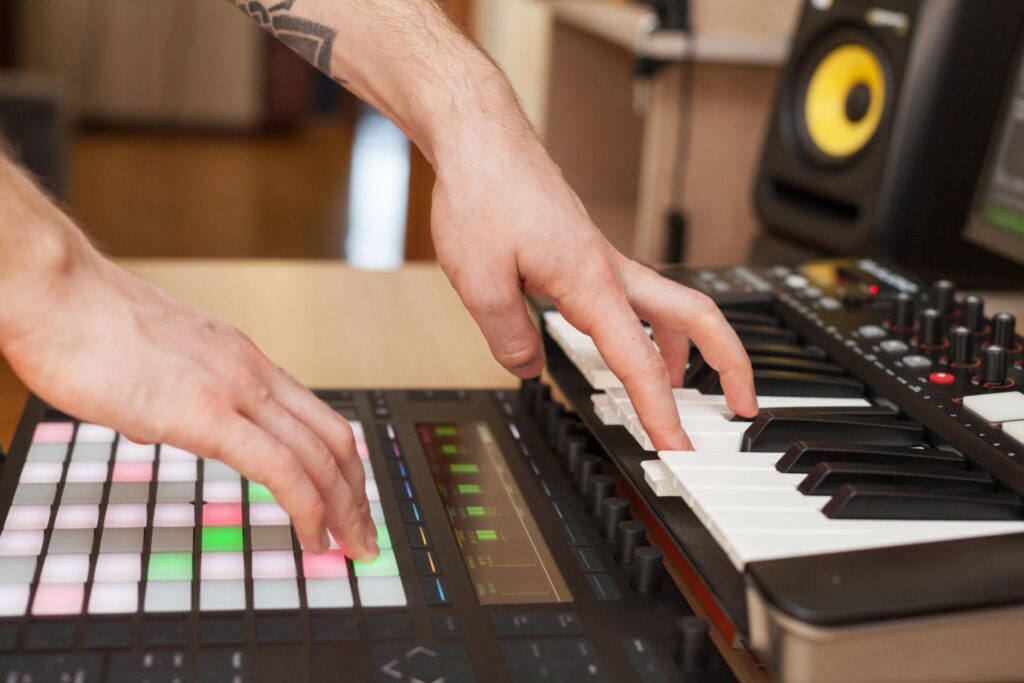 Close-up view of synthesizer knobs, piano keys, and electronic sound controls in a professional studio environment.