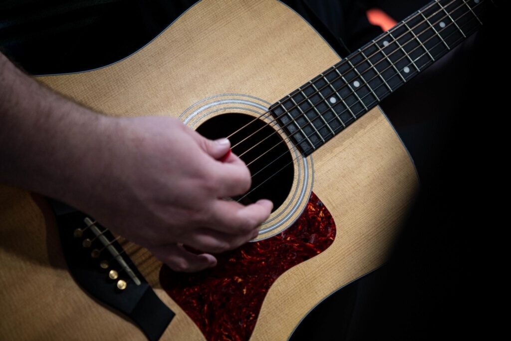 Acoustic guitar player during worship practice, representing Building a Guitar Section for Your Church Worship Team with focus on rhythm, teamwork, and musical worship leadership.