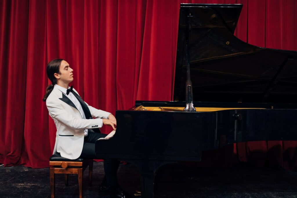 "Pianist practicing on a grand piano in a music studio, building confidence and skills to overcome piano performance anxiety."