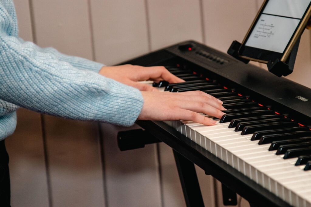 Hands playing simple worship chords on a piano.