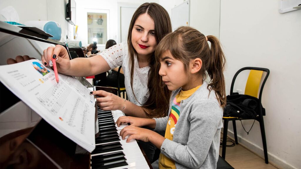 Piano teacher guiding a student in reading sheet music.