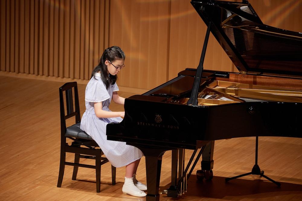 Young piano student confidently performing at a piano recital.