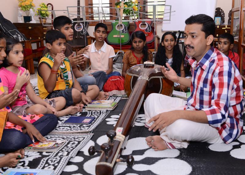 Carnatic music teacher helping a student improve vocal technique, pitch accuracy, and musical expression.